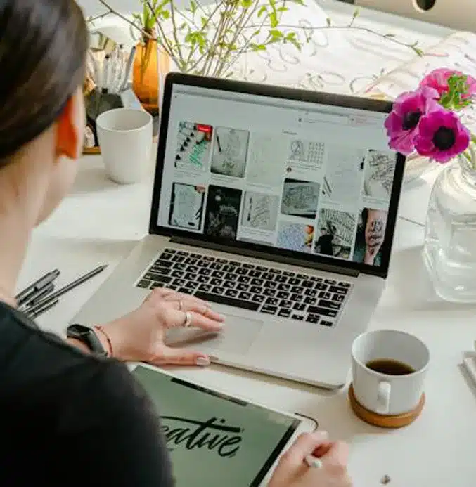 woman working on designs on a laptop and sketchpad